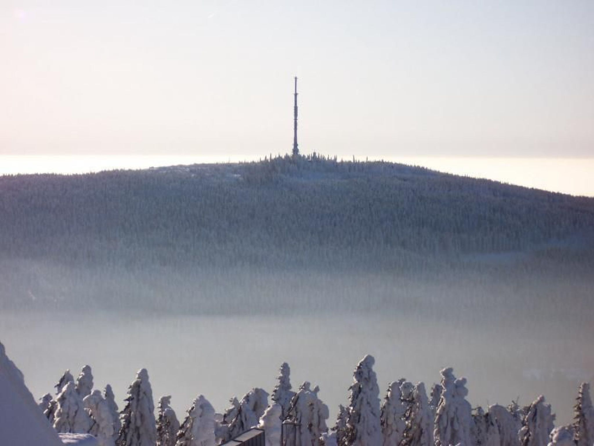 A snow-covered landscape with a solitary communication tower on a hill.