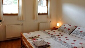 Une chambre avec deux lits, un plancher en bois, un radiateur et une fenêtre avec des rideaux.