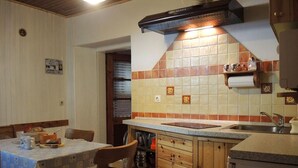 Une cuisine compacte avec un coin repas, des meubles en bois, un four encastré et un pare-feu en carreaux.