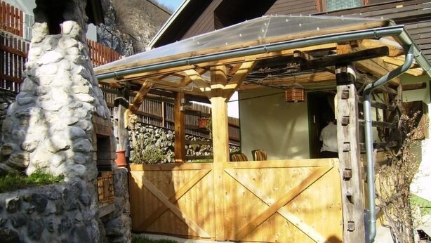 Un bâtiment rustique en bois, doté d’un mur en pierre et d’une clôture en bois.