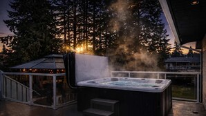 A hot tub with steam, surrounded by a covered patio with string lights. - The Stag House : HotTub, Outdoor Theatre, Arcade Games, Big Backyard & Sleeps 18 (Langley)