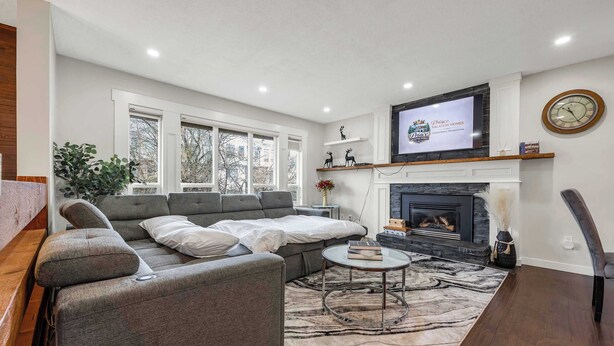 A modern living room with a sectional sofa, a fireplace, a television, and a large window. - The Stag House : HotTub, Outdoor Theatre, Arcade Games, Big Backyard & Sleeps 18 (Langley)