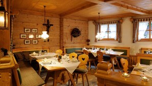Un interior de madera con mesas dispuestas para comer, bancos e iluminación colgante.