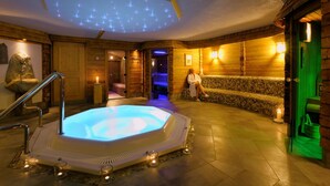 Un área de spa con una bañera de hidromasaje, paredes de madera y un banco de piedra.