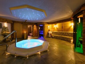 A spa area with a hot tub, wooden walls, and a stone bench. - Ruhige Wohnung im Ortszentrum by Interhome (Sankt Gallenkirch)