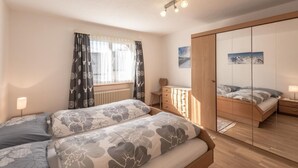 Un dormitorio con una cama, cómoda, espejo y ventana con cortinas.