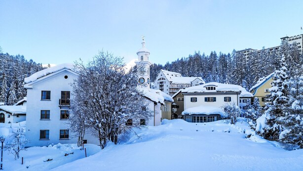 A snow-covered building with a clock tower, surrounded by trees and other buildings. - Studio Chesa Marias by Interhome (Sils Maria)