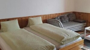 A room with a wooden bed, a sofa, and a small table. - Studio Chesa Marias by Interhome (Sils Maria)
