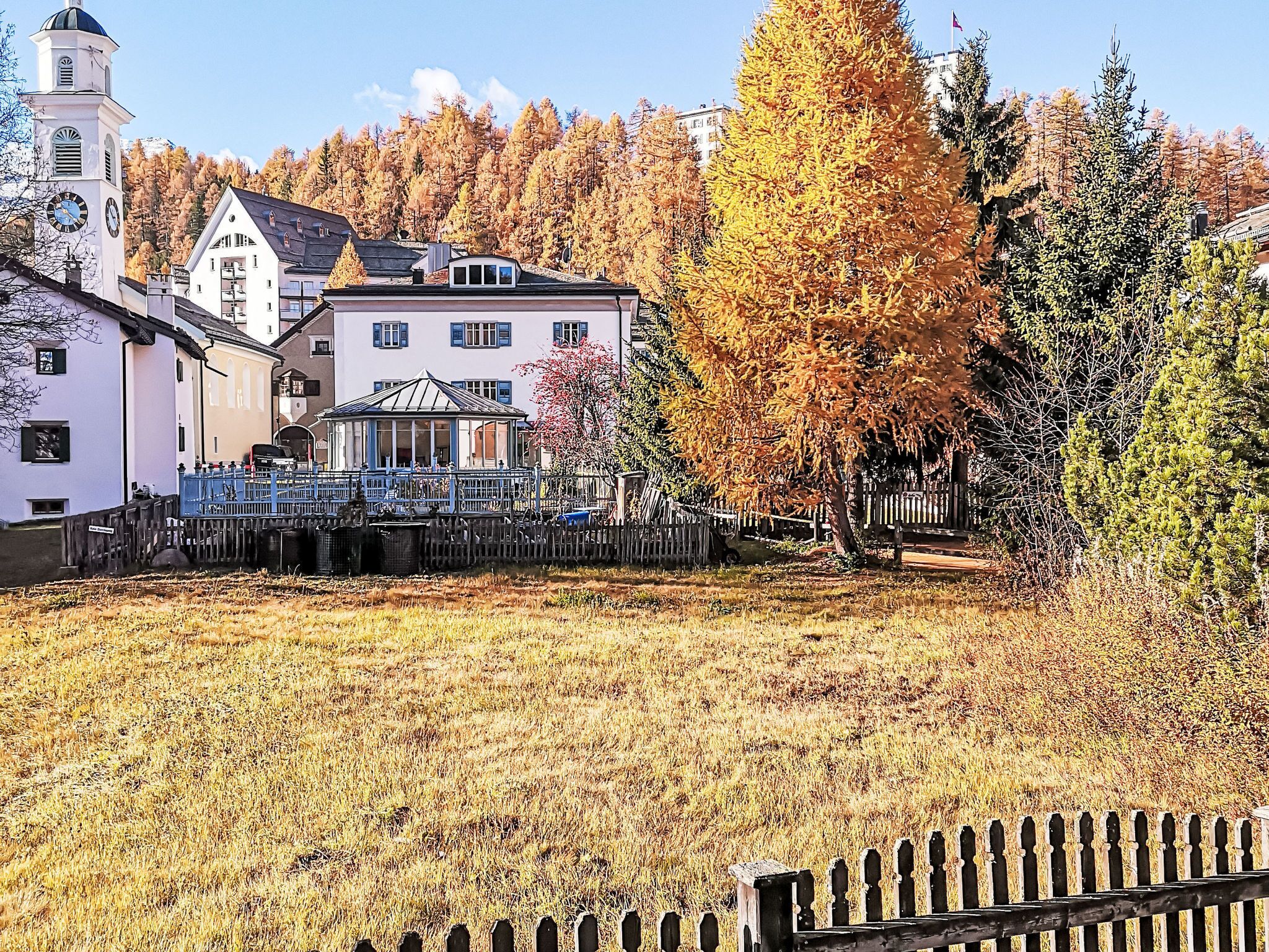 A town with a prominent church, a gazebo, and autumn-colored trees.
