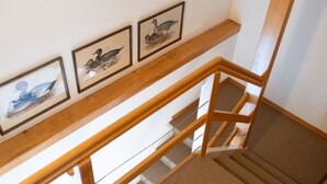 A wooden staircase with a carpeted landing and three framed pictures on the wall above.