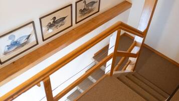 Eine Holztreppe mit Teppich belegter Zwischenebene und drei gerahmten Bildern an der darüberliegenden Wand.