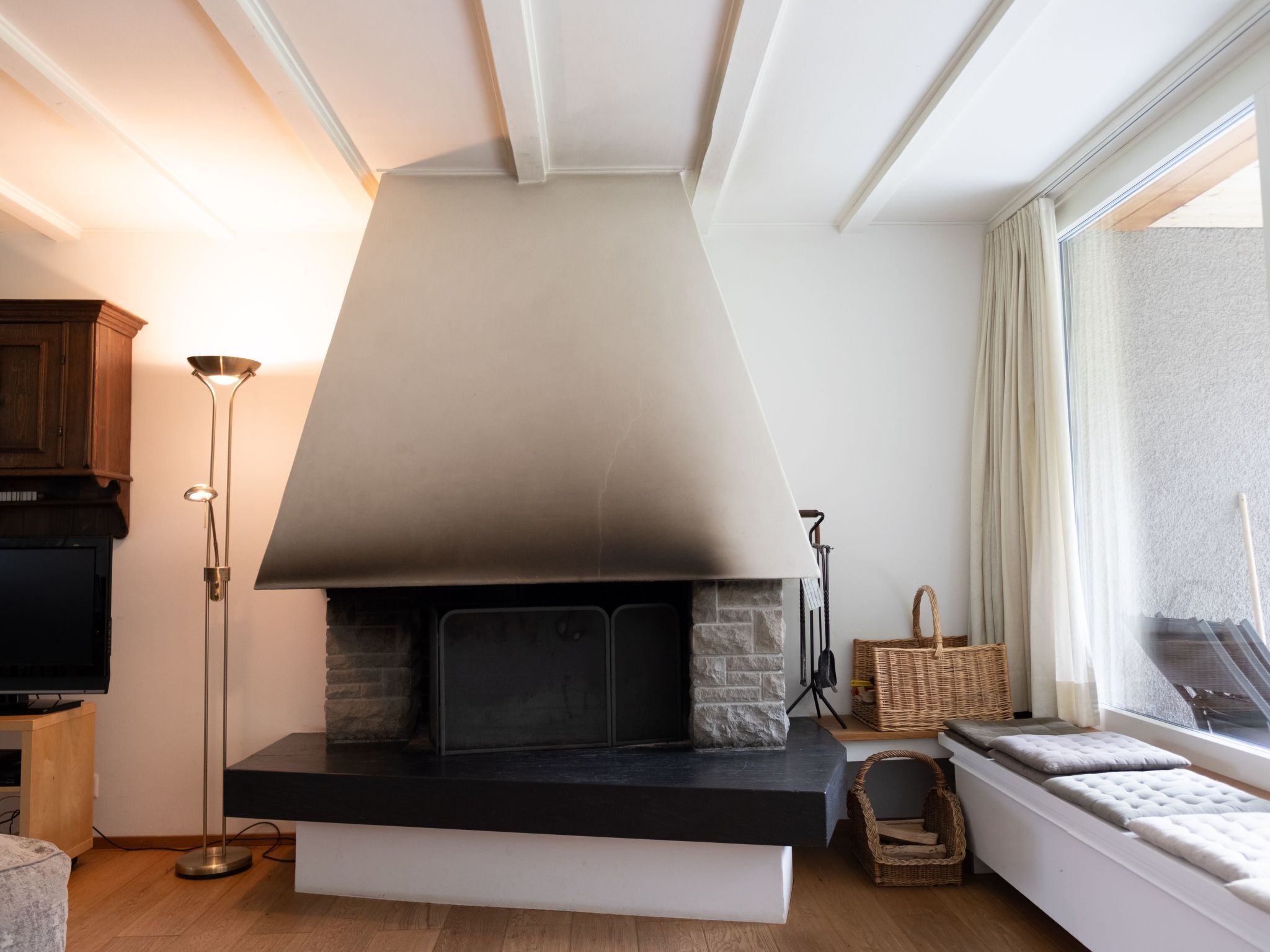 Ein modernes Wohnzimmer mit Kamin, Fernseher und großem Fenster.