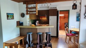 A compact kitchen with a bar area, wooden stools, and a dining table with chairs. - im Gründli by Interhome (Wildhaus)