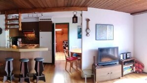 A compact living space with a kitchen area, a dining table, and a seating area with a TV. - im Gründli by Interhome (Wildhaus)