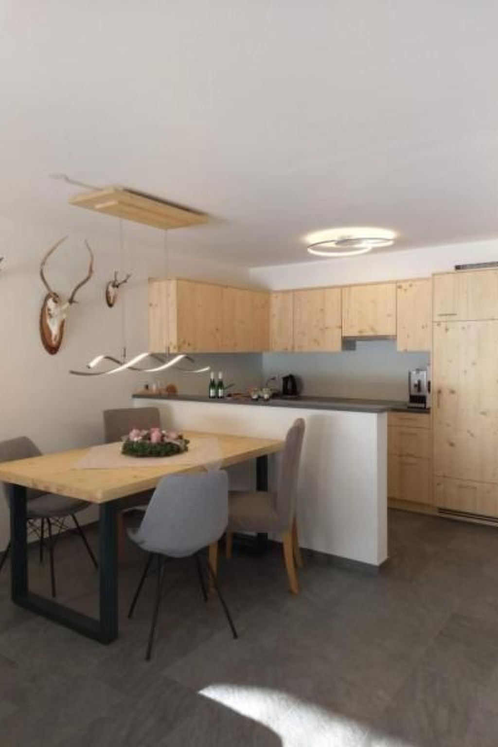 A modern kitchen with wooden cabinets, a central island, and a dining area with chairs.