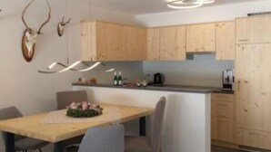 Una cocina moderna con armarios de madera, una isla central y un comedor con sillas.