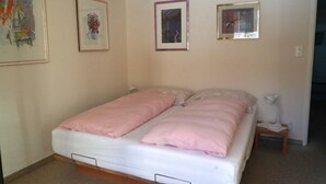 Ein Schlafzimmer mit einem Bett, zwei gerahmten Bildern an der Wand und einem Nachttisch mit einer Lampe.