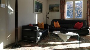 Ein Wohnzimmer mit einer schwarzen Couch, einem Couchtisch, einer Stehlampe und einem gemusterten Teppich.