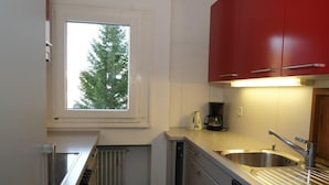 Eine kleine Küche mit Fenster, einer Kaffeemaschine und einem Geschirrspüler.
