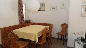 Ein Essbereich mit einem Holztisch, Stühlen, einer hängenden Leuchte und gerahmten Bildern an der Wand.