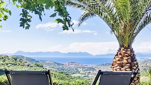Two chairs facing a scenic view with mountains and a body of water in the distance.