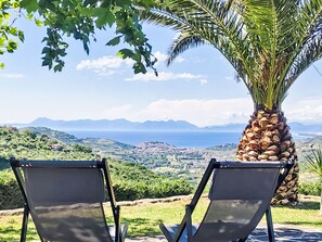 Deux chaises sont placées face à un paysage magnifique, avec des montagnes et une étendue d’eau qui se dessine à l’horizon.