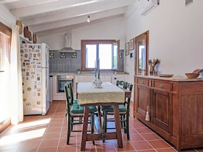 Una cuina amb taula de dinar, cadires, nevera i finestra.