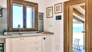 Una cocina con ventana, un lavamanos, lavavajillas y una puerta que da a un espacio exterior.
