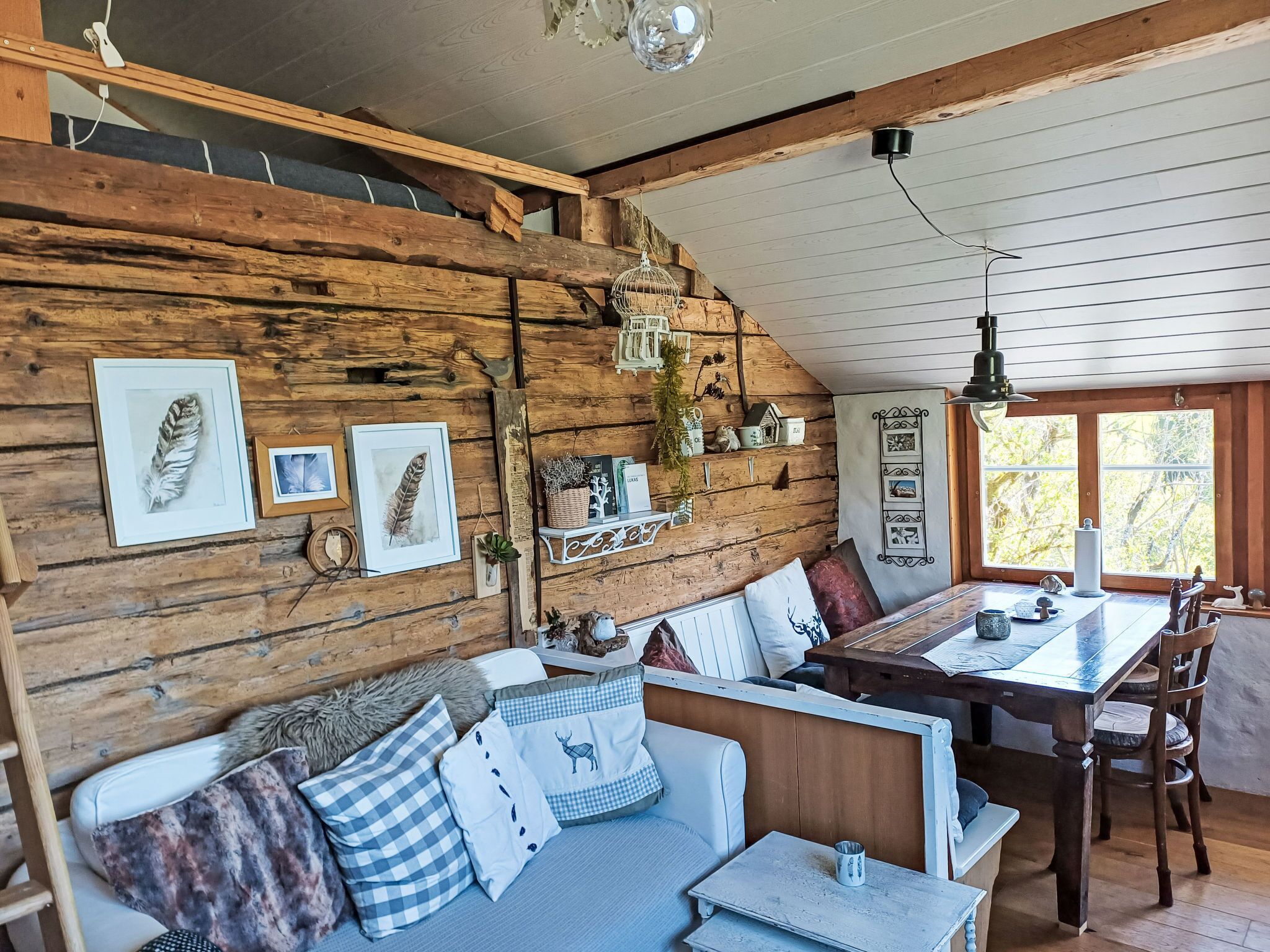 Un interior de cabaña acogedor, con una pared de madera, una zona de comedor y un espacio en altillo.