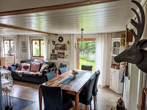En hyggelig stue med et træbord, en sofa med dekorative puder og en stor dekoration af et dådyrshoved.