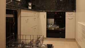A modern kitchen with white cabinets, a black countertop, and a built-in dishwasher. - Casa Uccello by Interhome (Wildhaus)