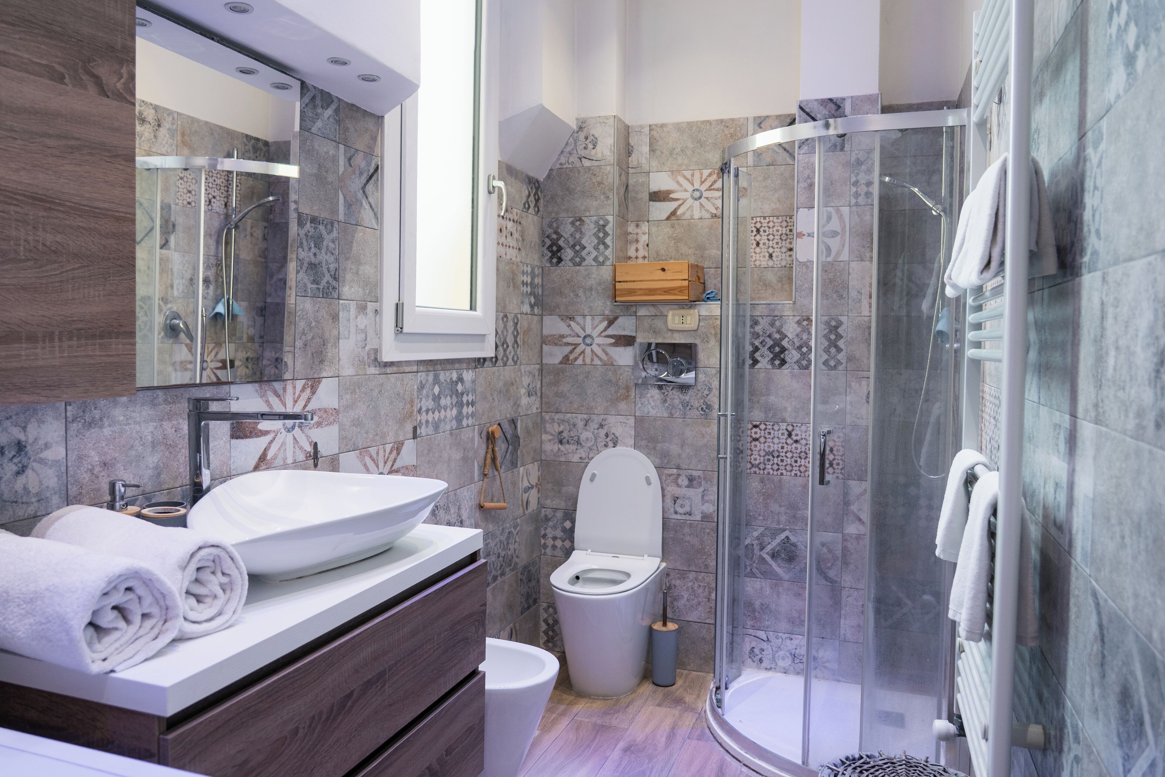A modern bathroom with a glass-enclosed shower, a wooden vanity, and a white sink.