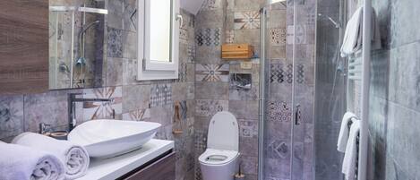 A modern bathroom with a glass-enclosed shower, a wooden vanity, and a white sink.