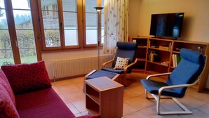 A living room with a sofa, two armchairs, a coffee table, a TV, and a bookshelf. - Engi 484j by Interhome (Hasliberg)