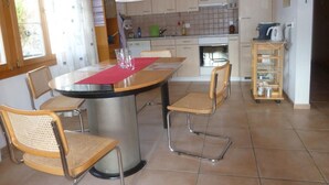 A modern kitchen with a dining area, featuring a round table, chairs, and a coffee machine. - Engi 484j by Interhome (Hasliberg)