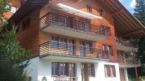 A multi-story wooden building with balconies, large windows, and a covered outdoor area. - Engi 484j by Interhome (Hasliberg)