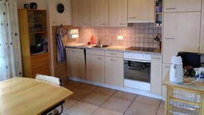 A compact kitchen with wooden cabinets, a built-in oven, and a coffee machine. - Engi 484j by Interhome (Hasliberg)