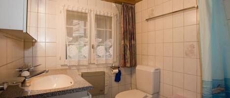 A bathroom with a sink, toilet, and shower curtain.