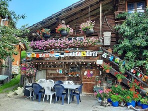 Ein rustikales Holzhaus mit einem Balkon, geschmückt mit hängenden Blumenampeln und verschiedenen Flaggen.