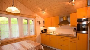 Una cocina con armarios de madera, una estufa y una ventana con persianas.