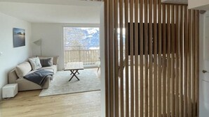 A modern living room with wooden slats, a sofa, a coffee table, and a hanging light fixture. - Sunnehöckli by Interhome (Hasliberg)