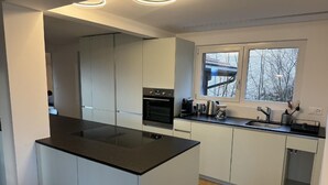 A modern kitchen with a central island, built-in oven, and a window providing a view of the outdoors. - Sunnehöckli by Interhome (Hasliberg)