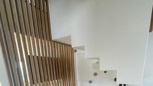 A modern interior with a wooden slat partition, a blue and a pink ottoman, and a white wall with a small shelf. - Sunnehöckli by Interhome (Hasliberg)