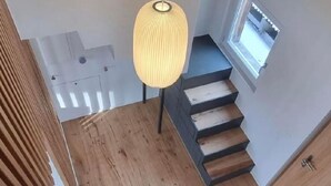 A wooden staircase with a modern pendant light, a small window, and a door. - Sunnehöckli by Interhome (Hasliberg)