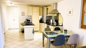 A compact kitchen with a dining area, featuring a small island, a stove, and a sink. - Pfrundmatte 12 by Interhome (Aeschi bei Spiez)