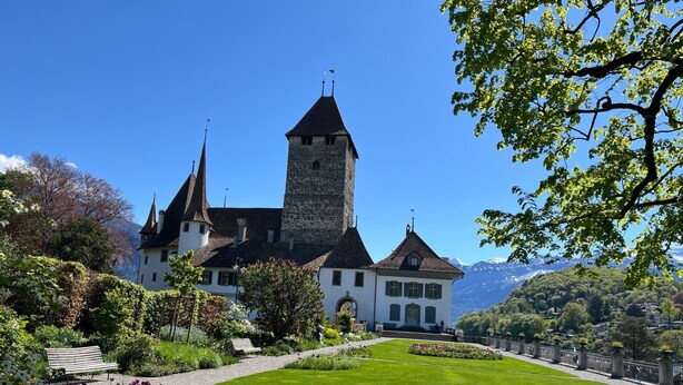 A historic building with a prominent tower, surrounded by well-maintained gardens and a clear view of mountains in the background. - Pfrundmatte 12 by Interhome (Aeschi bei Spiez)