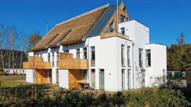 Una casa moderna con tetto spiovente, ampie finestre e dettagli in legno.