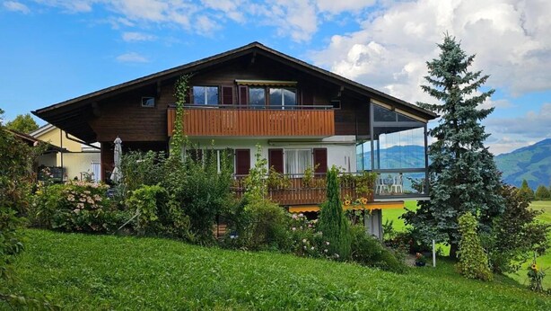 A two-story wooden house with a balcony, surrounded by lush greenery and a clear sky. - Chalet Alouette by Interhome (Aeschi bei Spiez)
