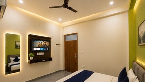 Ein modernes Schlafzimmer mit einem Bett, einem an der Wand montierten Fernseher, einem Deckenventilator und einer Tür.