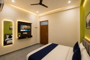 Een moderne slaapkamer met een bed, een tv aan de muur, een plafondventilator en een deur.